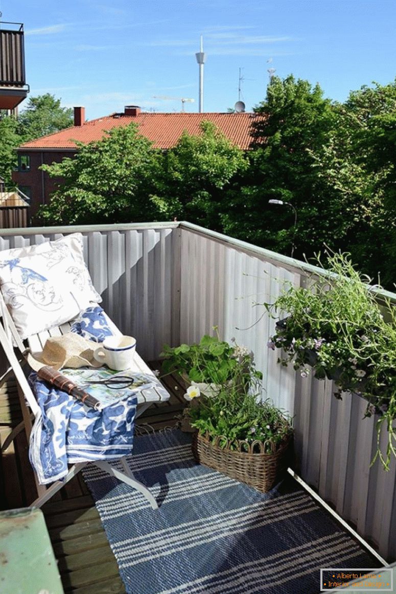 małe patio-design-z białą-ławką-również-niebieską-bawełnianą-wzorkiem-dywan-obok-białym-balustradowym-balustradą