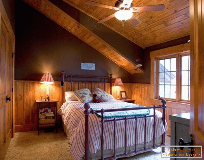 Sypialnia gościnna na poddaszu w stylu chatki jest przestronna i nie jest zbyteczna z elementami dekoracyjnymi.