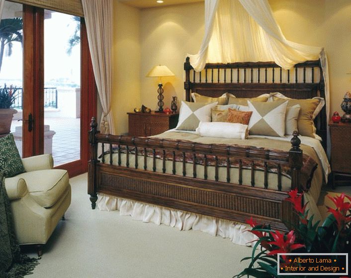 Luksusowe łóżko w sypialni w stylu eklektyzmu. Baldachin nad łóżkiem, lekkie zasłony na drzwiach prowadzących na werandę sprawiają, że pokój jest przytulny i romantyczny. 