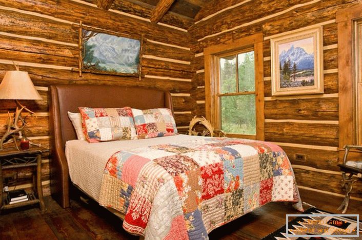 Sypialnia w rustykalnym stylu w domku myśliwskim. Godna uwagi dekoracja ścian przy pomocy domu z bali. 
