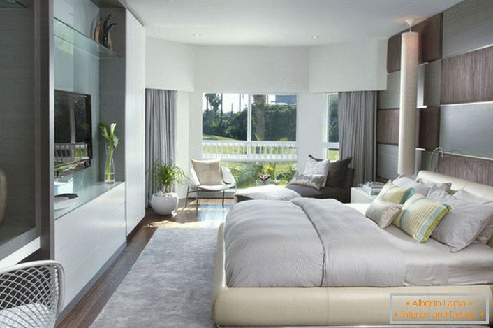 Miękkie, masowe łóżko w sypialni w nowoczesnym stylu. Meble o błyszczącej powierzchni dobrze komponują się z ogólną kompozycją wnętrza.