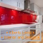 Białe meble i czerwony fartuch we wnętrzu kuchni