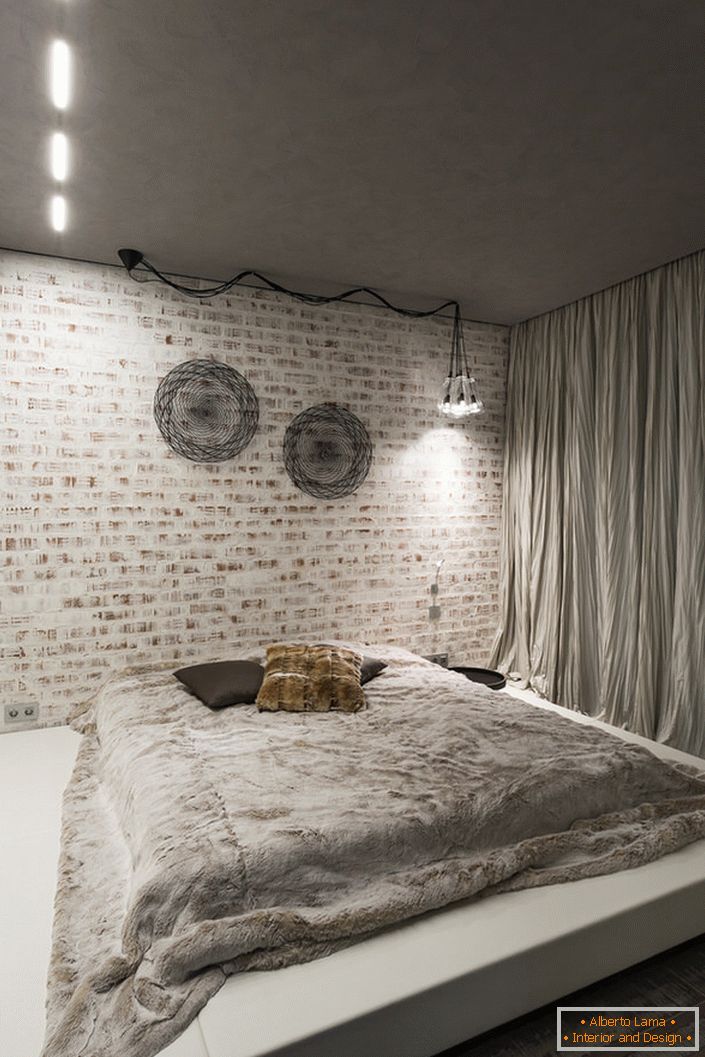 Sypialnia w stylu loftu powinna zawierać w swoim wnętrzu minimum mebli. Dobrym pomysłem na tę koncepcję stylu jest duże miękkie łóżko na niskim podeście.