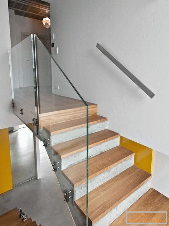Betonowe schody z drewnianymi schodami i szklaną balustradą w prywatnym domu