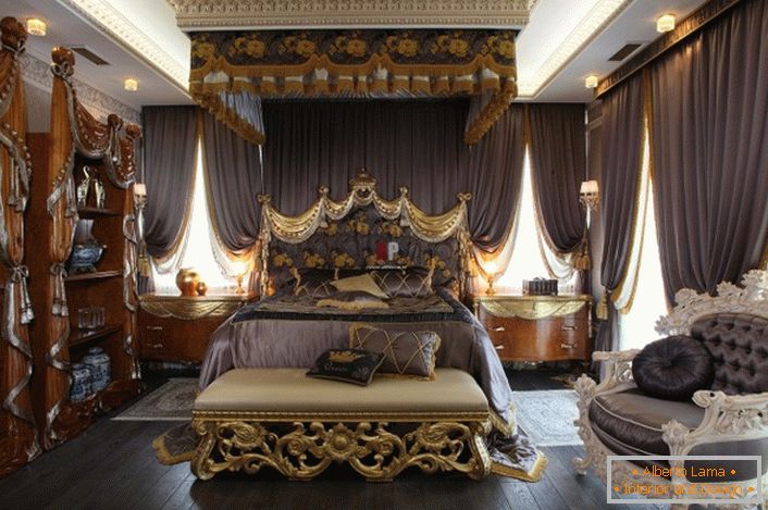 Luksusowa sypialnia w stylu barokowym. Pośrodku kompozycji znajduje się ogromne łóżko z wysokim zagłówkiem.