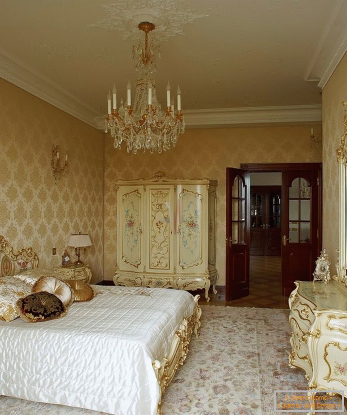 Elegancki żyrandol i sufit ze stiukiem harmonijnie łączą się z drewnianymi meblami w złotych kolorach. 