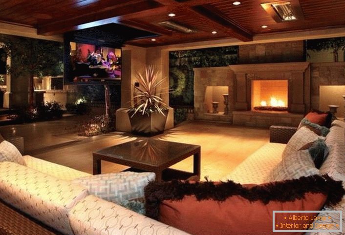 Stylowy pokój gościnny w nowoczesnym stylu rustykalnym ozdobiony jest dużym kominkiem. Drewniane sufity są organicznie dopasowane do ogólnego wnętrza.