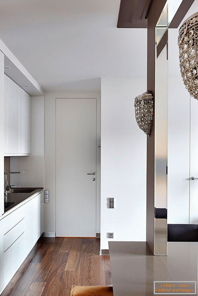 Białe meble kuchenne, białe drzwi wejściowe i piękny drewniany parkiet