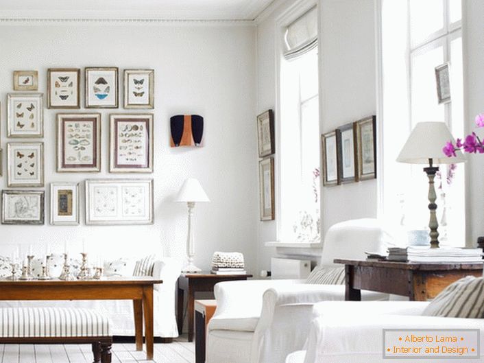 Przytulny salon w skandynawskim stylu wykonany jest w kolorze białym. Ciekawie jest ozdobić ścianę ramkami o różnych rozmiarach.