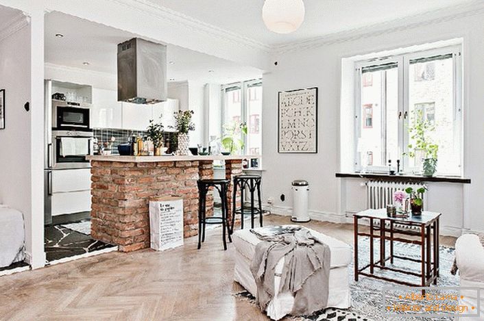 Apartament typu studio urządzony jest w skandynawskim stylu. Kuchnia oddzielona jest od salonu blatem barowym wykonanym z cegły.