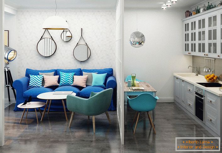 Ciemnoniebieska sofa kontrastuje z lekkim wykończeniem. Przykład udanego projektu małego jednopokojowego mieszkania.