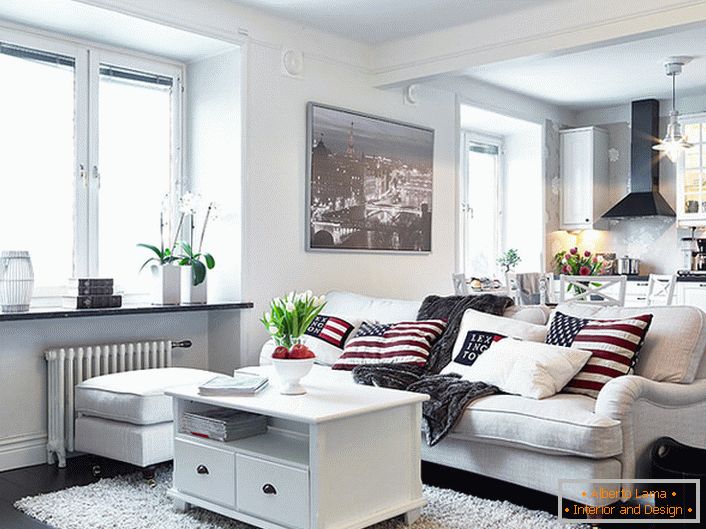 Przytulny apartament typu studio w stylu skandynawskim urządzony jest głównie w kolorze białym. Okna bez zasłon umożliwiają wejście do pomieszczenia wystarczającej ilości światła dziennego.