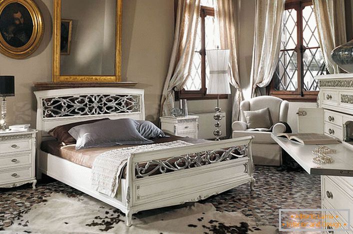 Zauważono podstawowy wymóg stylu barokowego. W przestronnej sypialni z wysokimi sufitami białe drewniane meble kontrastują z ciemnymi ramami okiennymi.