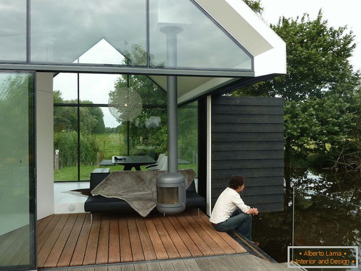 Taras małego szklanego domu nad jeziorem w Holandii