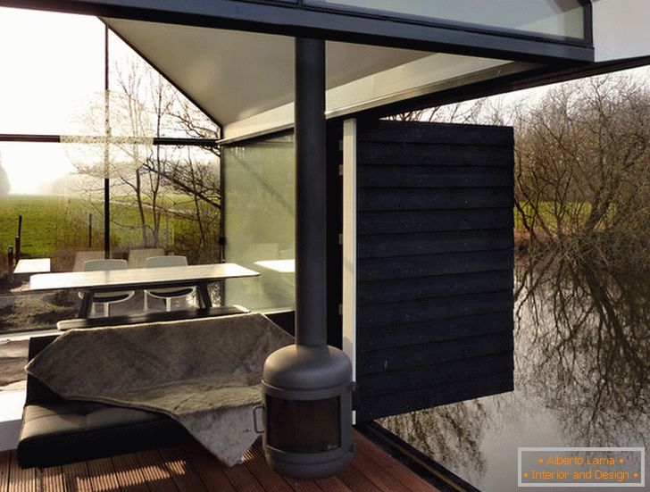 Taras małego szklanego domu nad jeziorem w Holandii