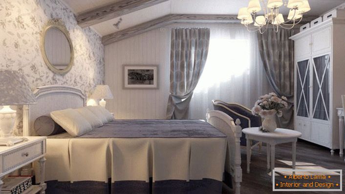 Sypialnia w wiejskim stylu wykonana jest w stonowanych, niebieskich odcieniach. Ściana u wezgłowia łóżka pokryta jest tapetą z motywem kwiatowym.