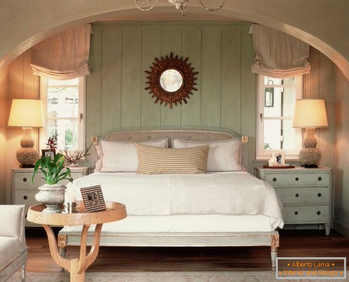 Sypialnia rodzinna w stylu wiejskim. Ciepło domu, jak to możliwe, podkreśla miękkie, objętościowe łóżko, pokryte poduszkami.