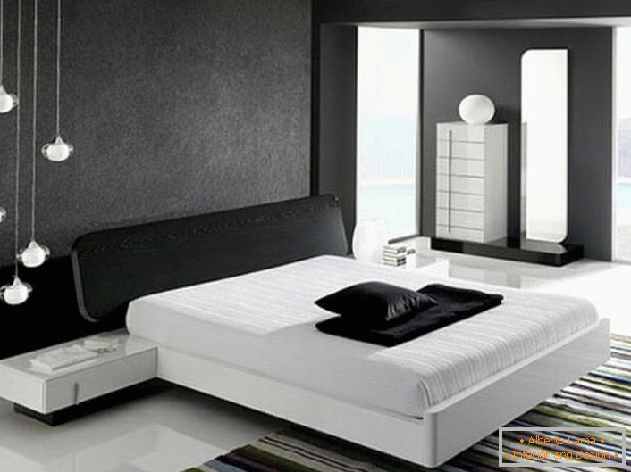 Ściana u wezgłowia łóżka ozdobiona szarą matową wstawką, zgodnie ze stylem hi-tech, harmonizuje z błyszczącą białą podłogą.