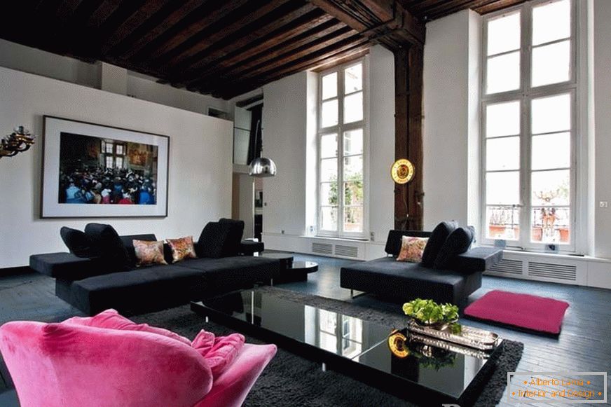 Czarne sofy i różowy fotel w pokoju