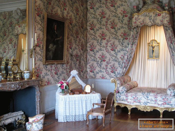 Kolorowa dekoracja ścian harmonizuje z tapicerką sofy i baldachimem nad nią. Barokowy salon z dużym kominkiem to świetny pomysł na wiejską rezydencję.