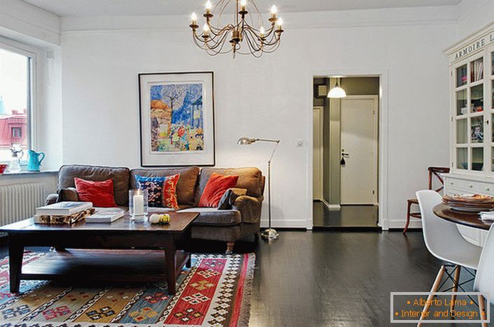 Stylowy pokój w typowym miejskim apartamencie ozdobiony jest jasnymi poduszkami na sofie i dywanie. 