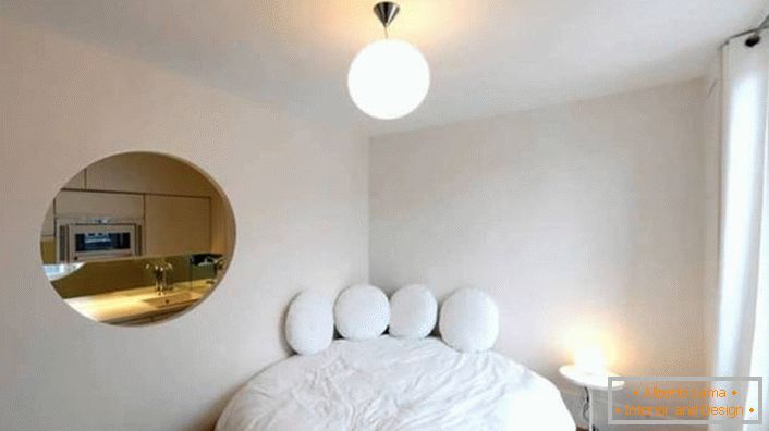 Pustka w ścianie owalnego kształtu sprawia, że ​​małe mieszkanie to luksusowe studio.