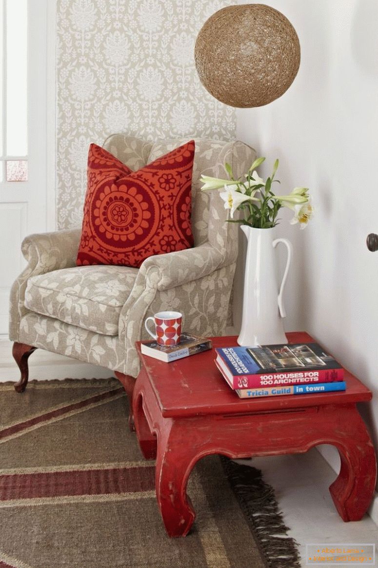 Czytanie kącik; Stół opiumowy i blady fotel ze wzorzystymi poduszkami rozproszonymi na ścianie z tapetami