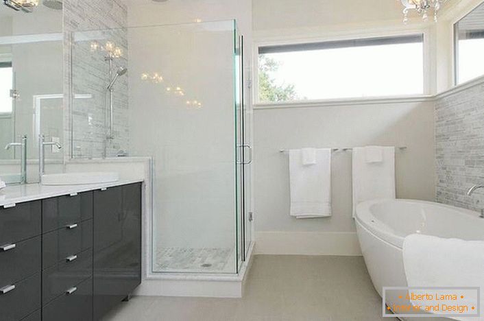 Przestronna modernistyczna łazienka z odpowiednim oświetleniem jest dekorowana przez słynnego projektanta z Francji. 
