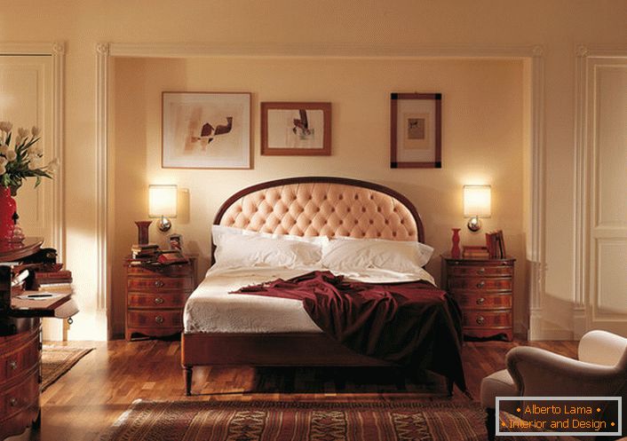 Szlachetny angielski styl w sypialni jest atrakcyjny i skromny. W centrum uwagi znajduje się łóżko w wysokim zagłówku, w którym znajduje się miękka, jasnobeżowa tkanina.