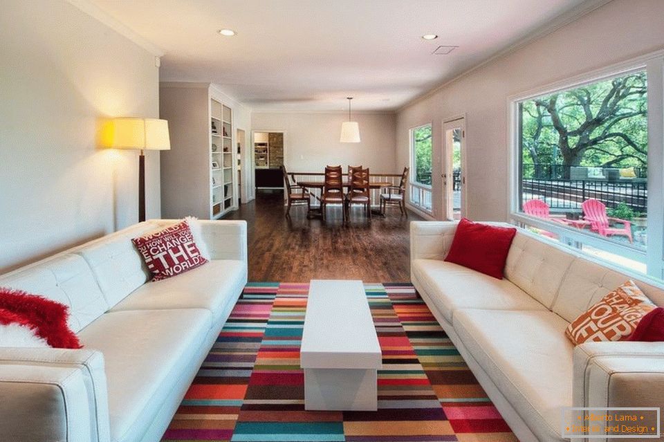 Pokój dzienny z białymi sofami i kolorowym dywanem