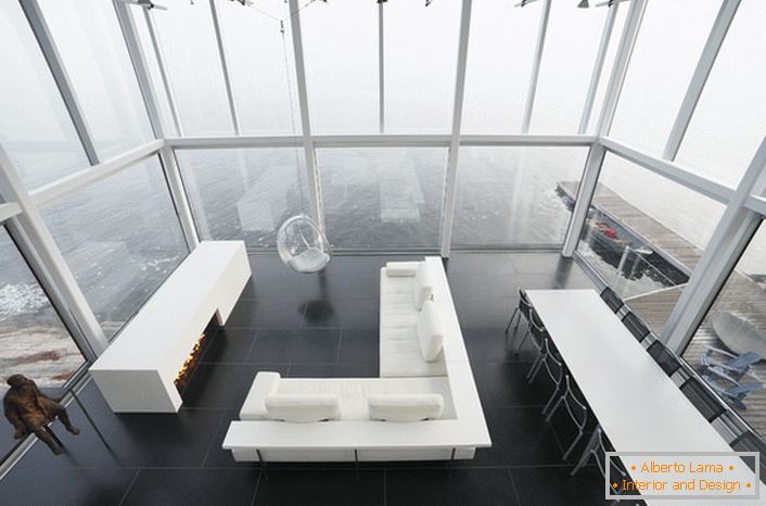 Lakoniczny wystrój salonu w minimalistycznym stylu. Ciekawym meblem jest krzesło zawieszone pod wysokim sufitem.