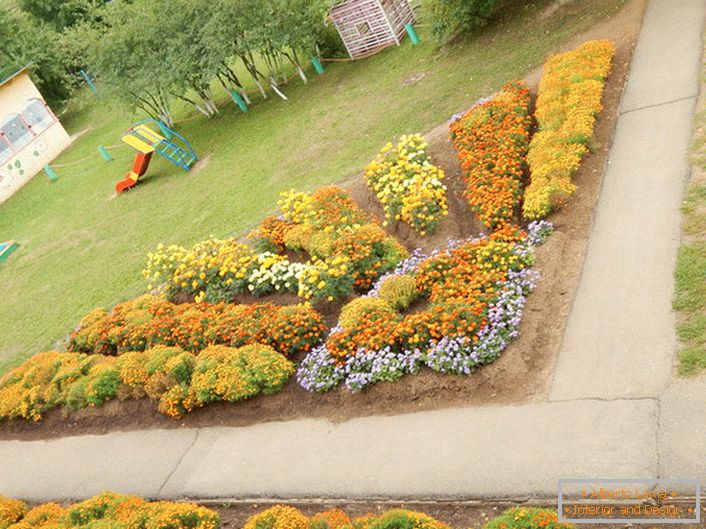 Modułowy ogród kwiatowy w formie promiennego słońca harmonijnie wygląda na placu zabaw.
