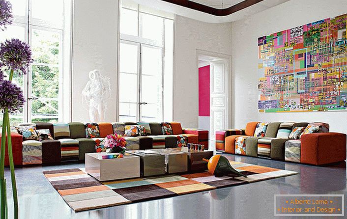Kolorowy pokój gościnny w awangardowym stylu w dużym domu włoskiej rodziny. Pomysł na projekt umiejętnie łączy wykładzinę dywanową i meble o zbliżonej skali kolorów.