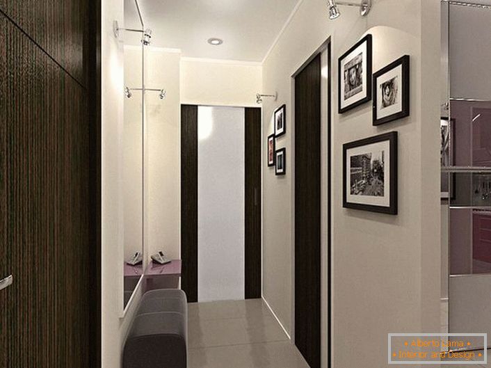 Rozwiązanie konstrukcyjne dla wąskiego korytarza. Dekoracja w kontrastujących odcieniach bieli i ciemnego brązu, nie tylko wygląda stylowo, ale także wizualnie sprawia, że ​​pokój jest bardziej.