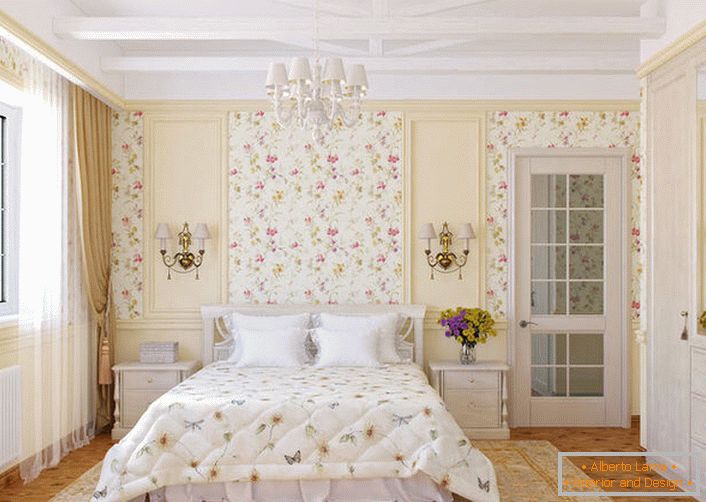 Ściany sypialni w stylu wiejskim ozdobione są tapetą z motywem kwiatowym, które harmonijnie wtapiają się w łóżko na łóżku.