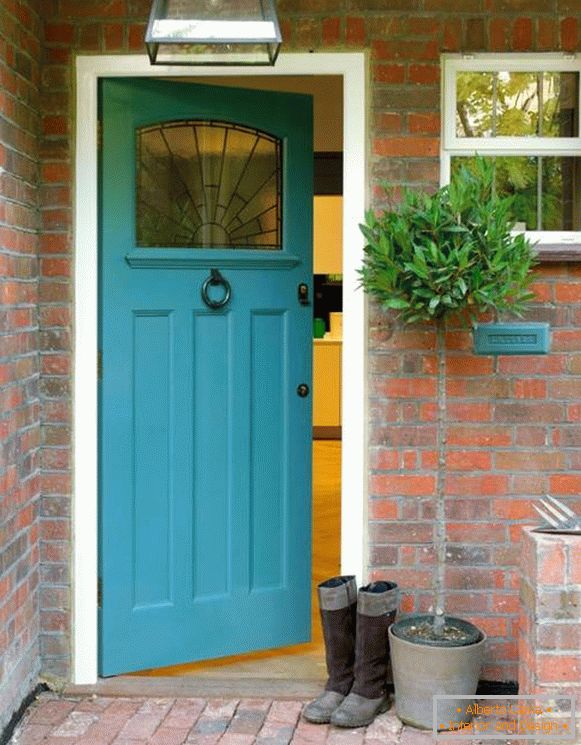 Niebieskie drzwi wejściowe do domu z czerwonej cegły