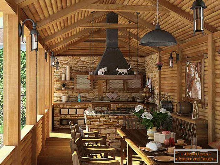 Mała kuchnia z grillem na werandzie wiejskiego domu. O stylu wiejskim świadczy przede wszystkim dekoracja ścian i sufitu za pomocą drewnianej ramy.